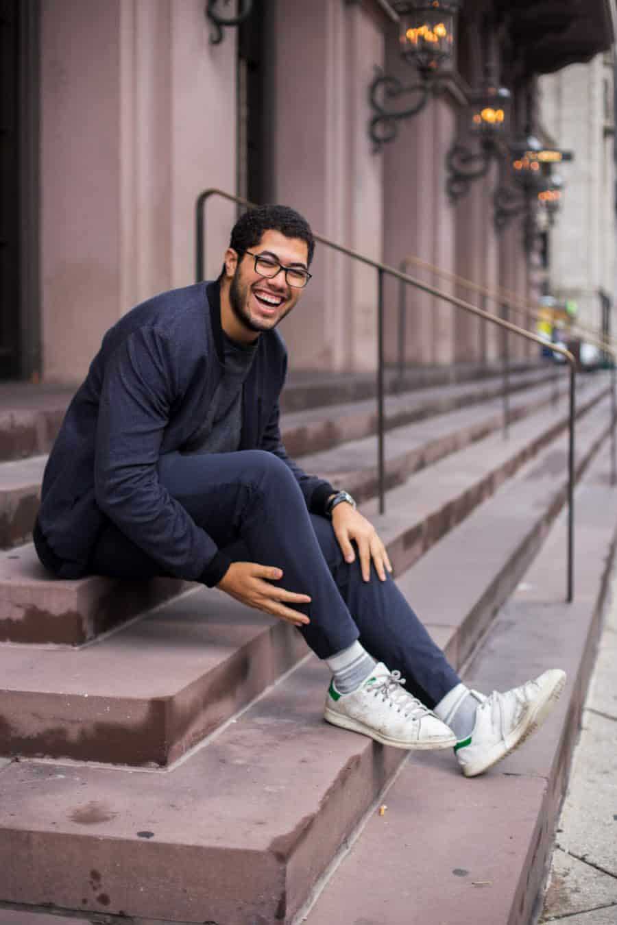 A happy young man sitting on steps outside of a building.